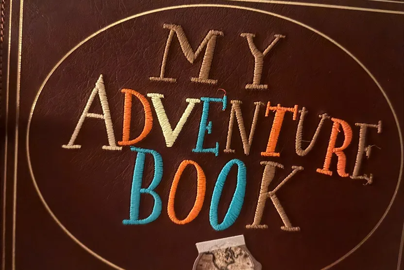 A leather journal embroidered with "My Adventure Book," like the one from the movie Up.